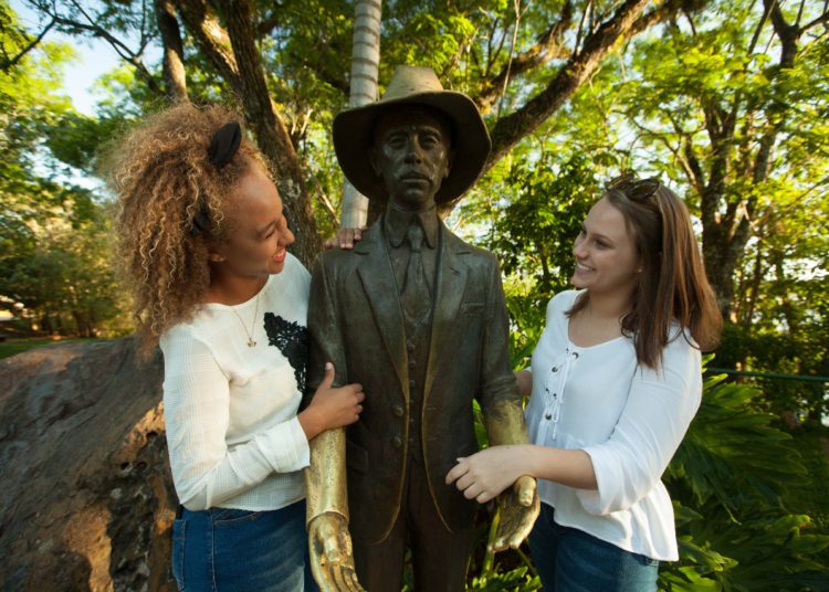 Turistas abraçam a estátua de Santos Dumont nas Cataratas do Iguaçu. Foto: Arquivo do Parque Nacional do Iguaçu/Divulgação