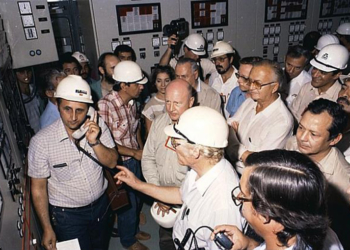Foto do momento em que José Pereira do Nascimento (ao telefone) está acionando a primeira unidade geradora da Itaipu, na presença do então diretor-geral brasileiro Costa Cavalcanti (de óculos e camisa branca, sem capacete) e do diretor-geral paraguaio na época, Enzo de Bernardi (de crachá vermelho e segurando o capacete) Foto: IB/Arquivo